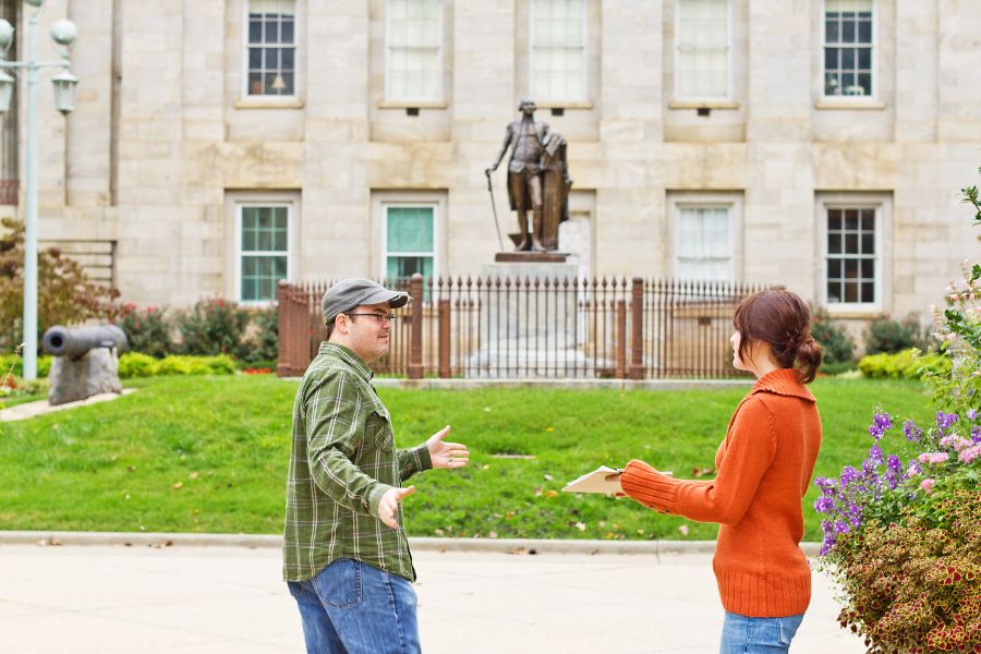 This is an image of a lady approaching a man with a petition clipboard.