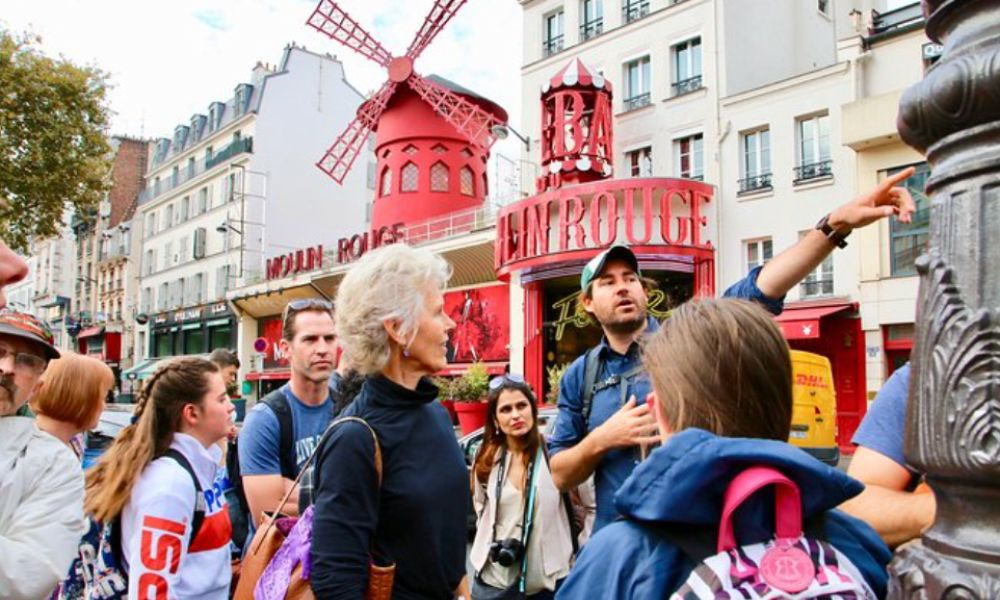 This is an image of a tour guide out the front of Moulin Rouge.