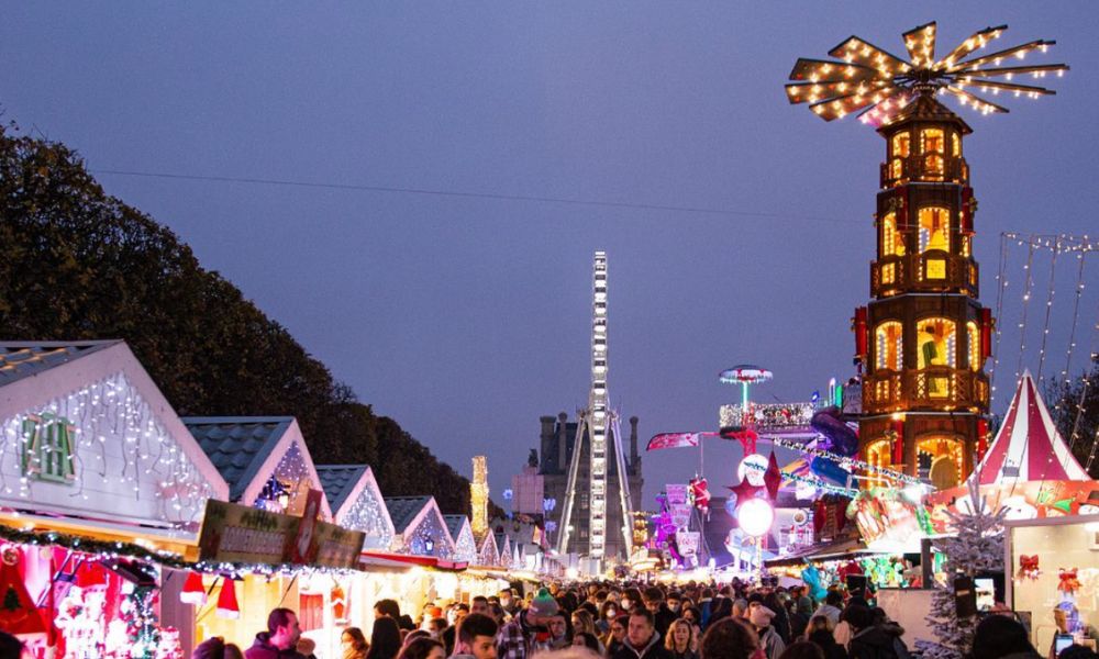 This is an image of a Christmas market with lots of lights and mini houses. It is quite crowded.