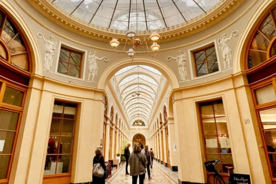 This is an image of one of the gorgeous passageways in Paris filled with shops and people.
