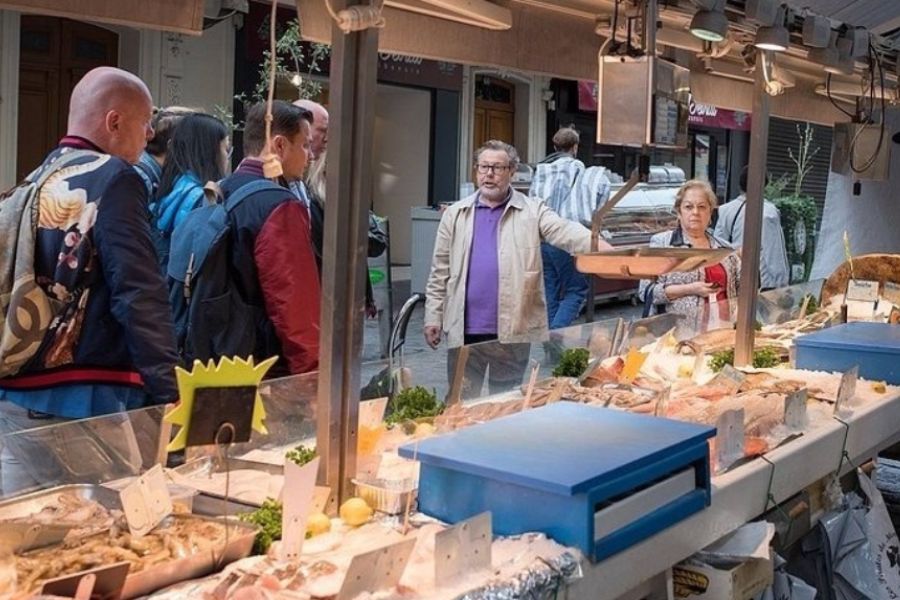 This is an image of a tour guide taking a tour group through a French food market before a cooking class.