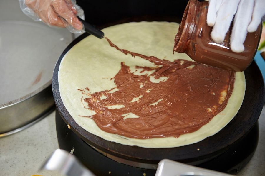 This is an image of someone putting nutella on a crepe.