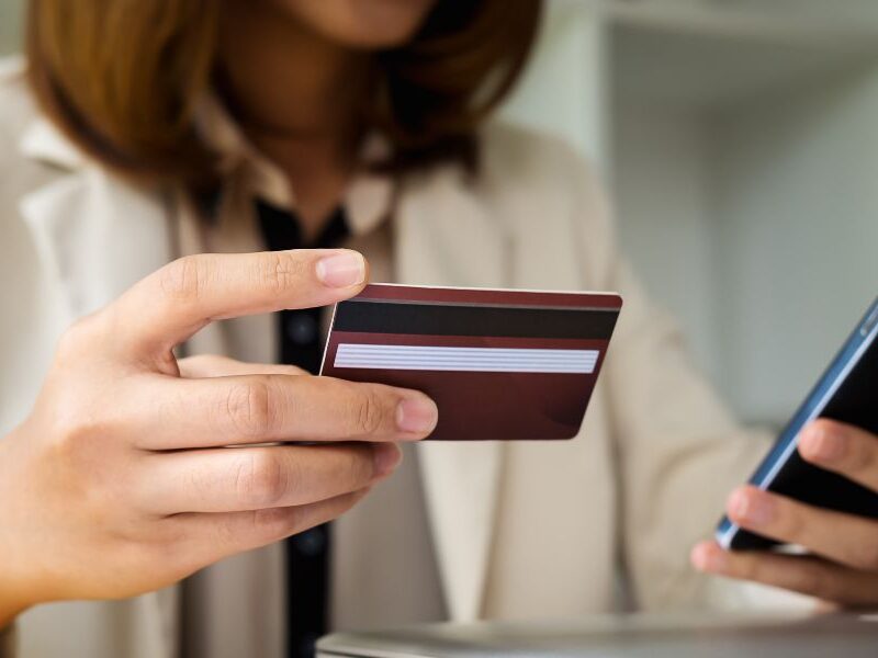 Best credit cards for Americans to use when visiting Paris: This is an image of someone looking at their credit card and holding their phone.