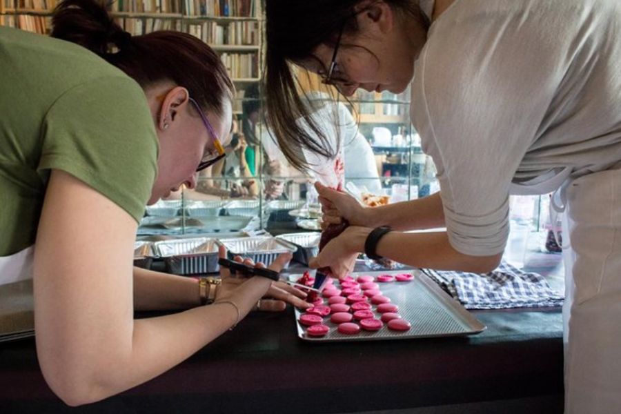 This is an image of two girls piping macaron filling on to a baking tray.
