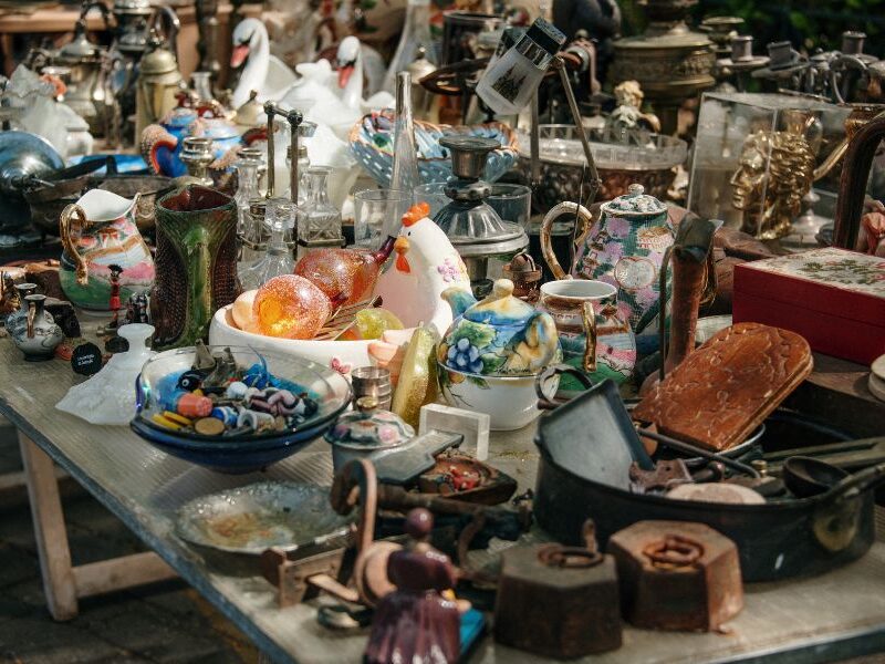 This is an image of a collection of dusty household wares and antiques laid out on a table.