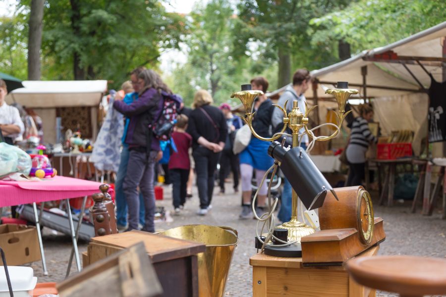 This is an image of a small street with a bunch of market stalls with people milling around.