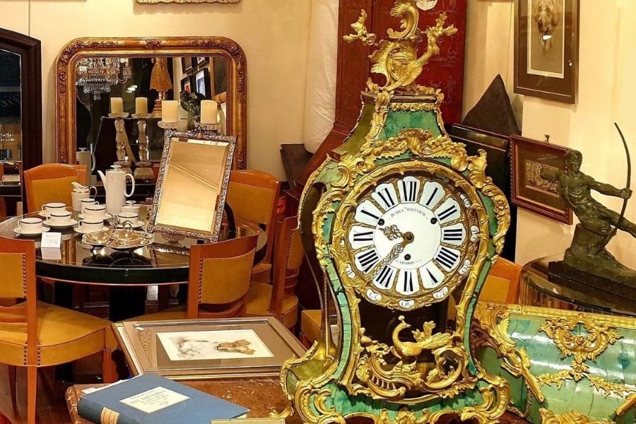 This is an image of a bunch of beautiful antique items in a showroom including a clock.