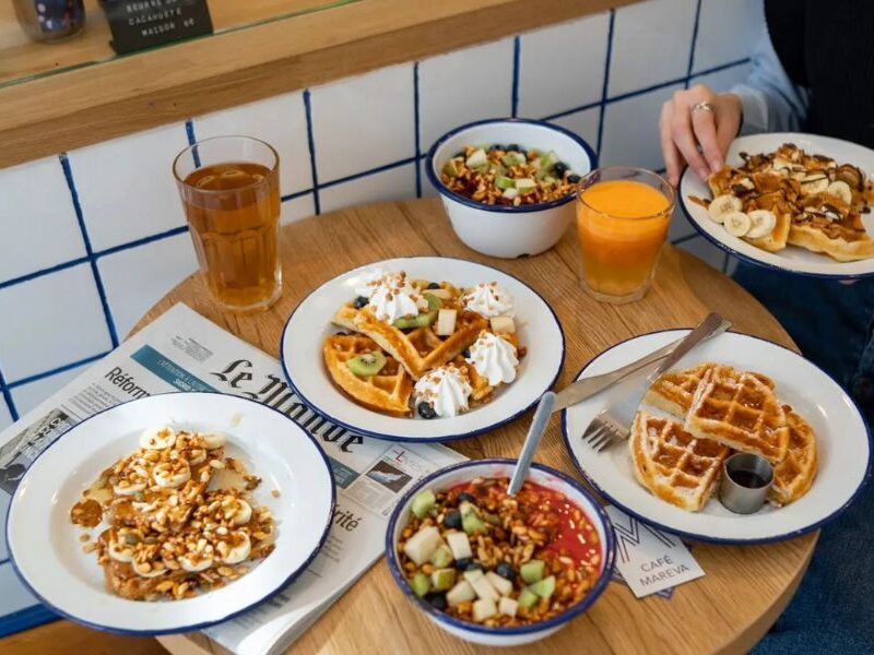 This is an image of a small table full of five cafe meals and a drink.