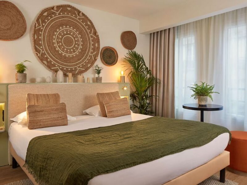This is an image of a boho-style bedroom with lot of greenery and straw decor.