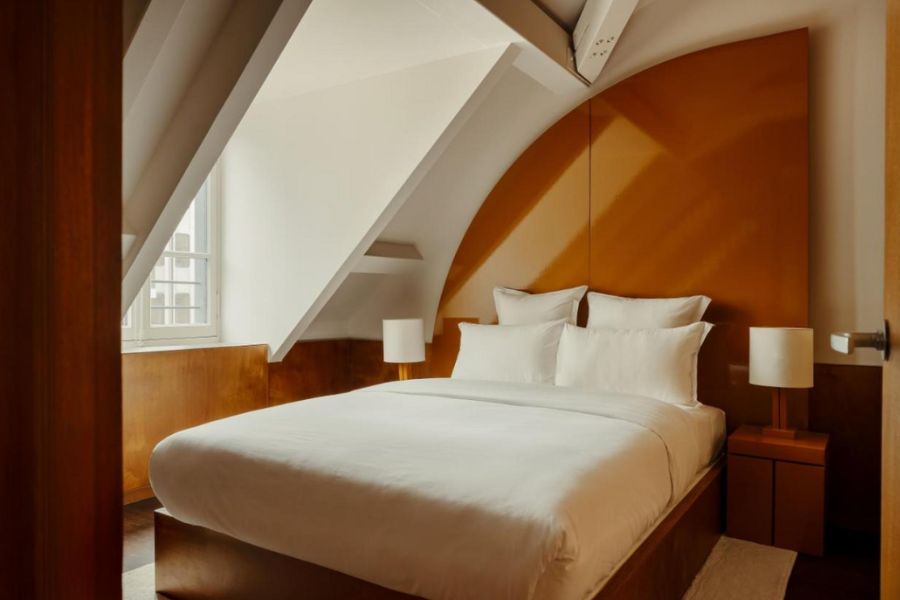 This is an image of a very minimalist hotel room with orange-toned wood as the accent colour on the walls.