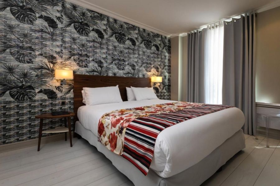 This is an image of a nice hotel room with a double bed, two bedside tables and a feature wall.