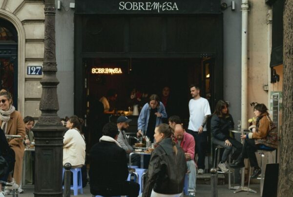 This is an image of a nice wine bar with people sitting outside at tables and talking.