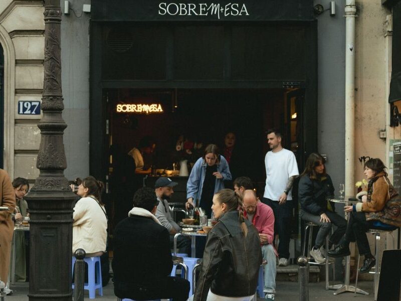 This is an image of a nice wine bar with people sitting outside at tables and talking.