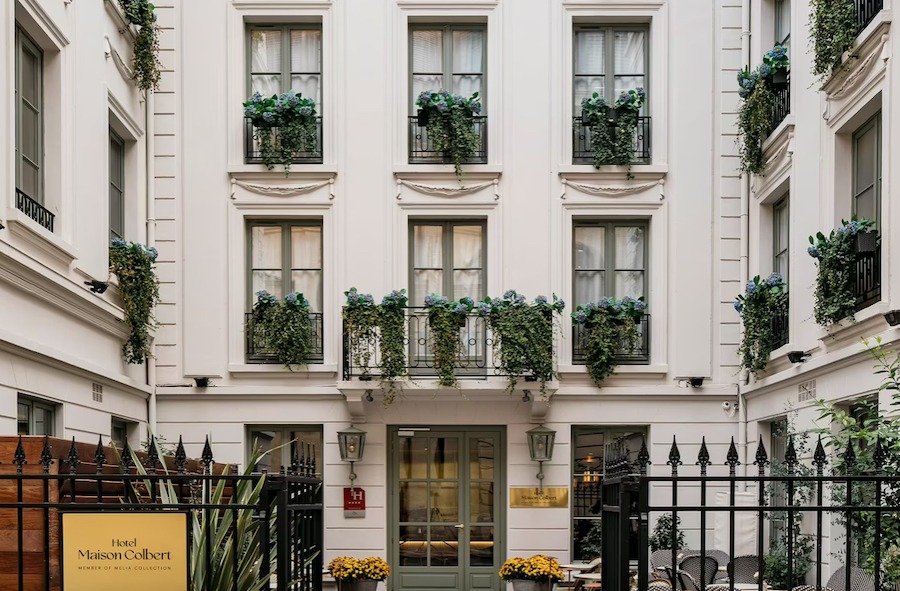 This is an image of the facade of a luxurious hotel with clean neutral walls and a black gate in front.