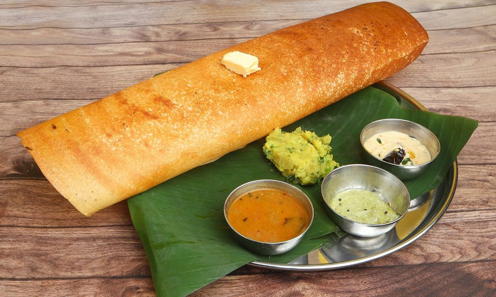This is an image of a crispy thin dosai with the side chutneys and sauces.