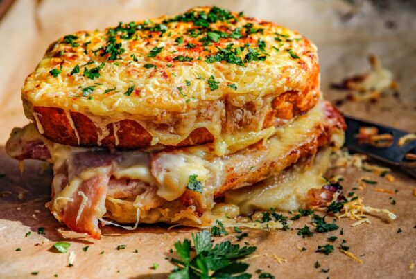 This is an image of a croque monsieur on a baking tray with crispy cheese and parsley.