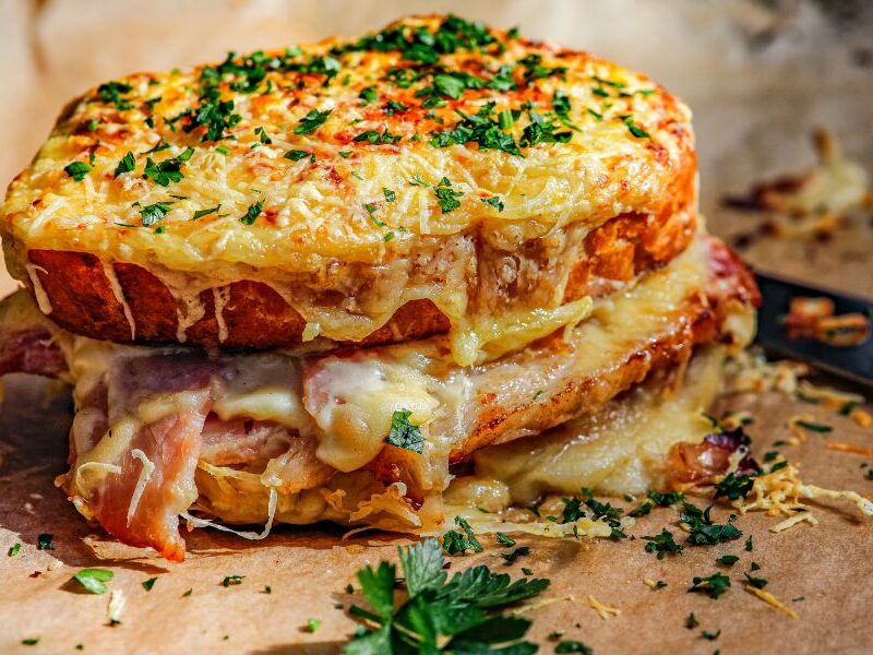 This is an image of a croque monsieur on a baking tray with crispy cheese and parsley.