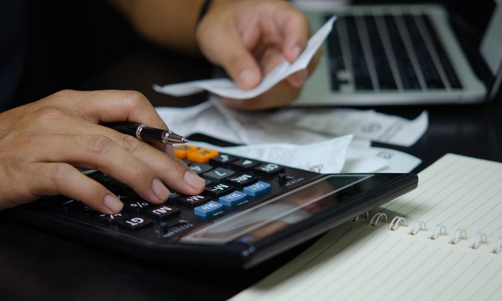 This is an image of someone using a calculator with a bunch of receipts.
