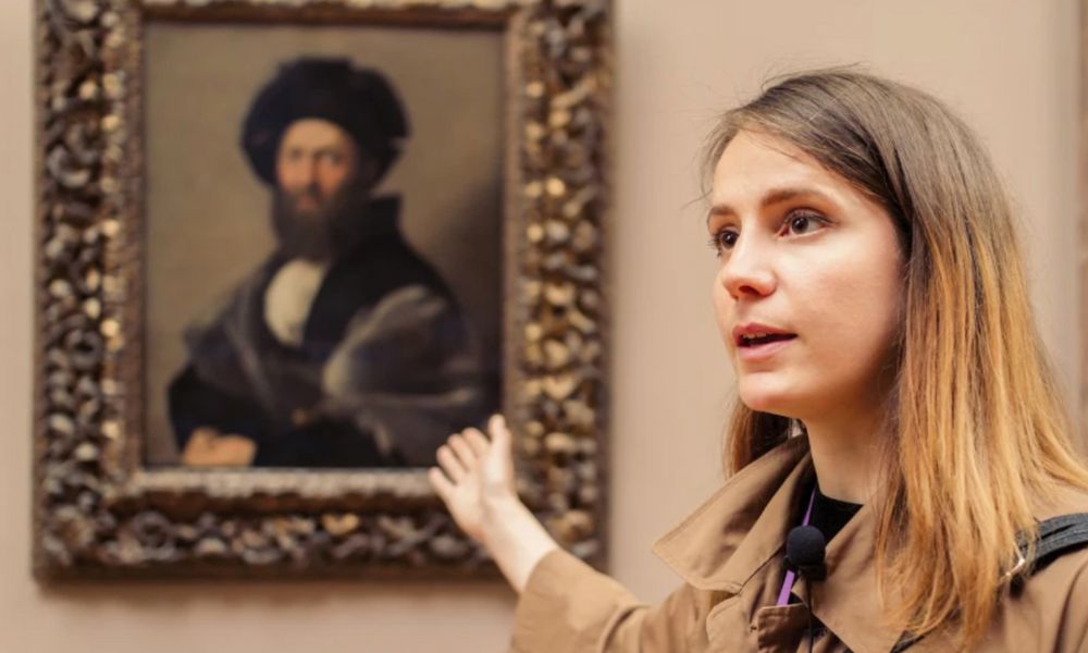 This is an image of a tour guide pointing at a picture on the wall.