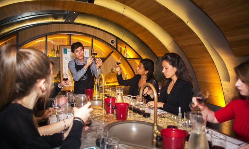 This is an image of a tour group making wine with a professional.