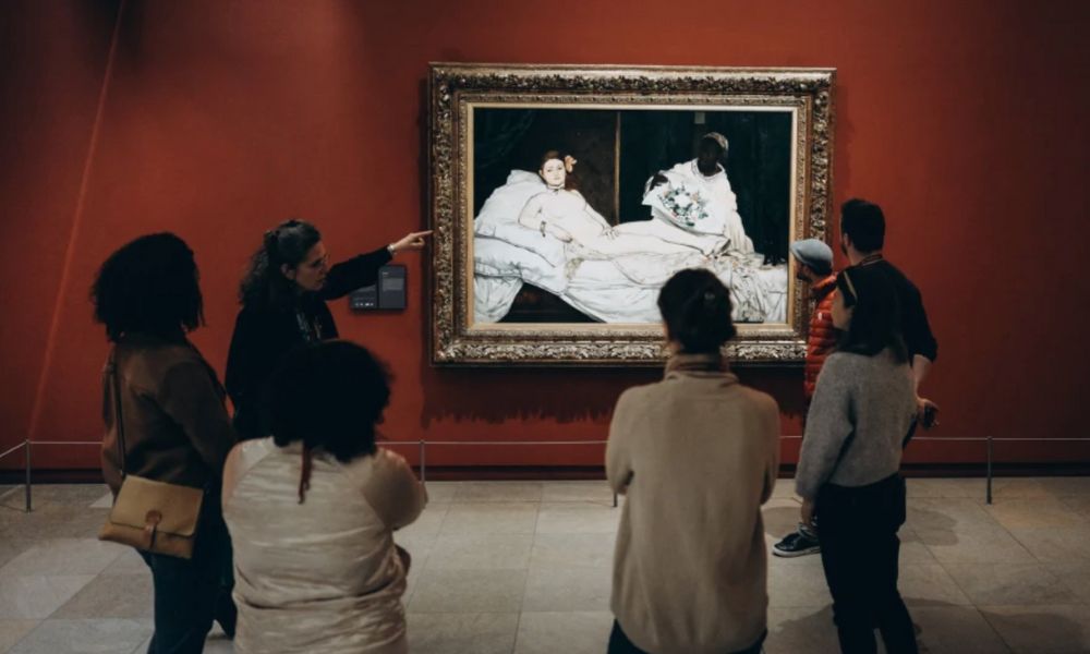 This is an image of a tour group gathered around a painting.