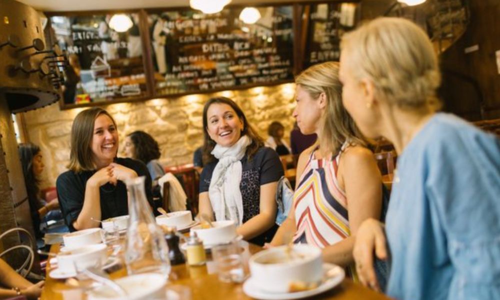 This is an image of people laughing together at the table and chatting with food.