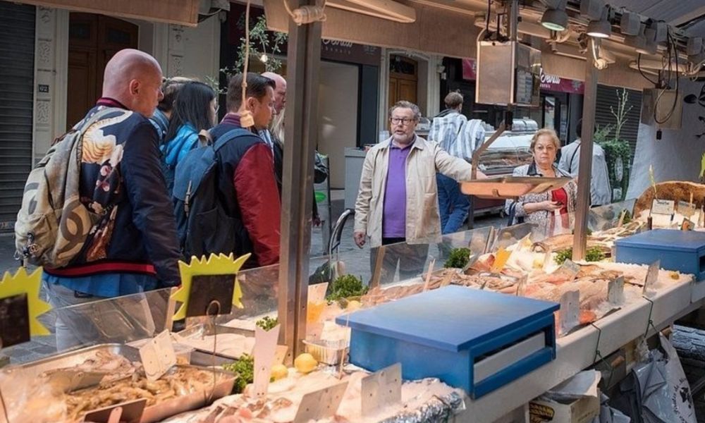 This is an image of a tour guide showing a tour group around a French fresh food market.
