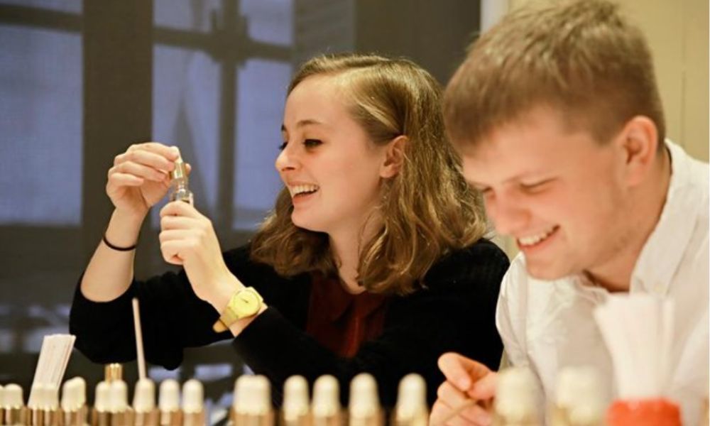 This is an image of a girl and guy looking through different bottles of scents to create their own perfume.