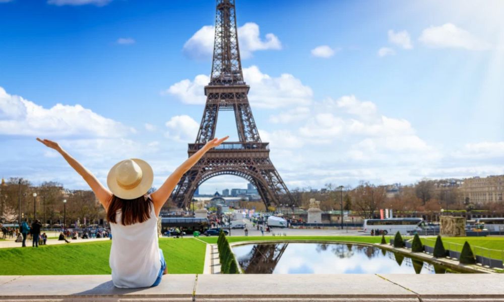 This is an image of a woman posing in front of the Eiffel Tower.