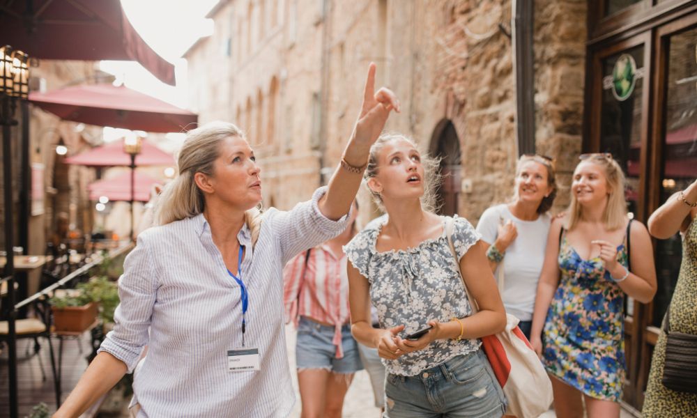 This is an image of a tour guide pointing up at a building with other people following her finger.