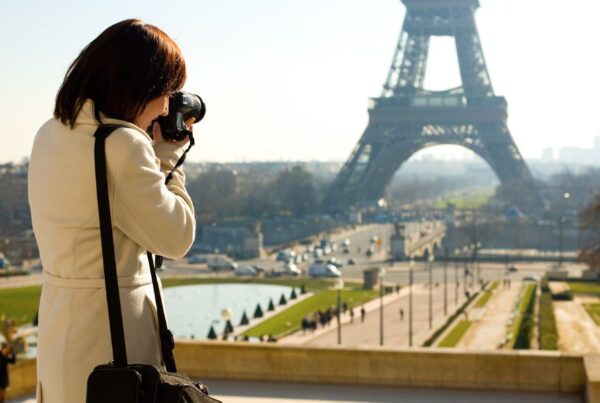 This is an image of a woman taking a picture of the Eiffel Tower on a big camera.