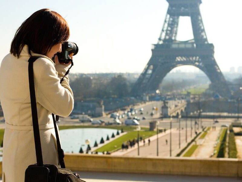 This is an image of a woman taking a picture of the Eiffel Tower on a big camera.