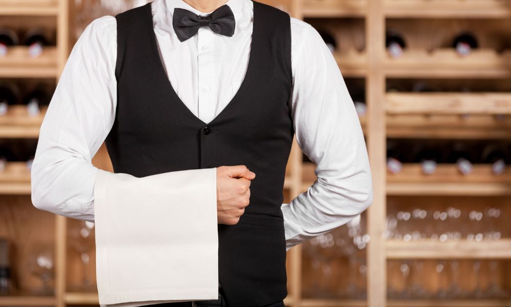 Things you should know before visiting Paris: This is an image of a waiter holding his hand up waiting to usher someone to their table.
