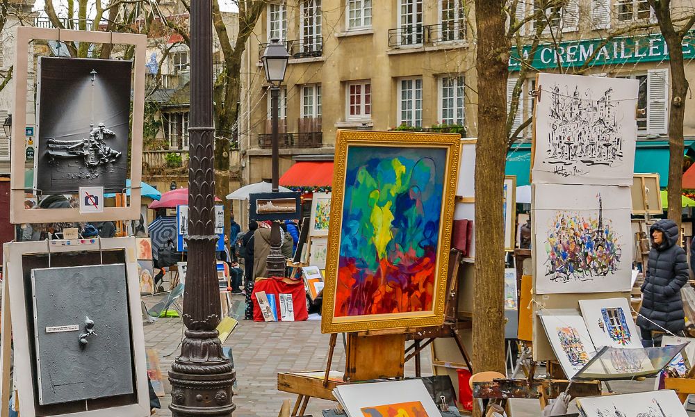 Things you should know before visiting Paris: This is an image of an art market in the middle of a Parisian square with canvases set up around the centre.
