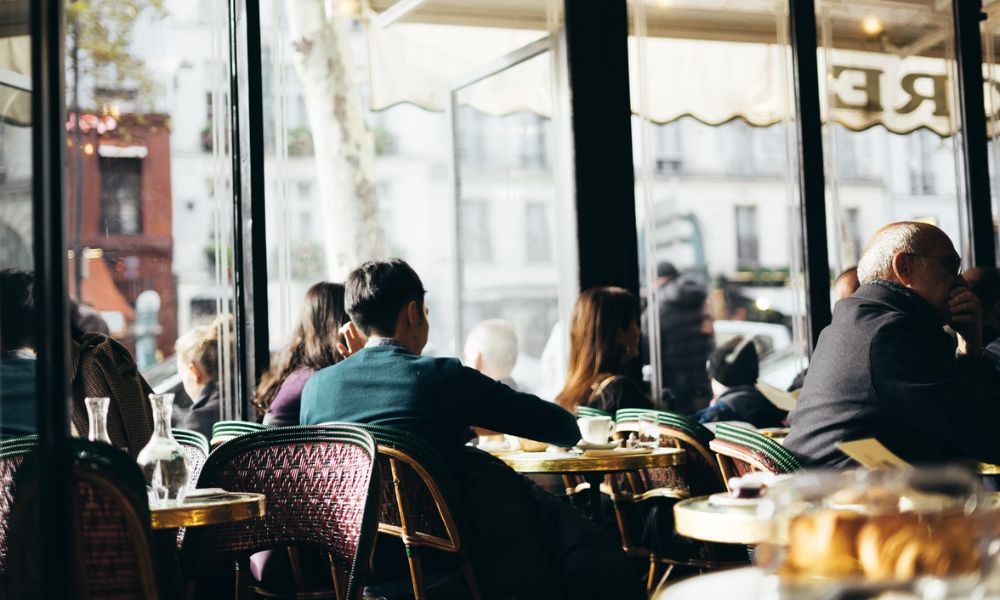 Things you should know before visiting Paris: This is an image of people sitting at a French restaurant talking and laughing.