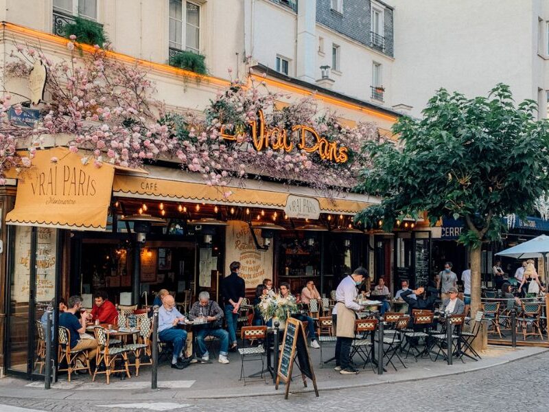 This is an image of a French café and restaurant that has outdoor seating and florals outside.