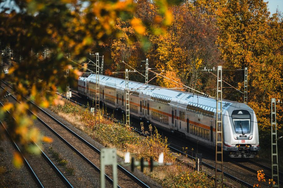 This is an image of a train rolling through the tracks with nice trees around it.