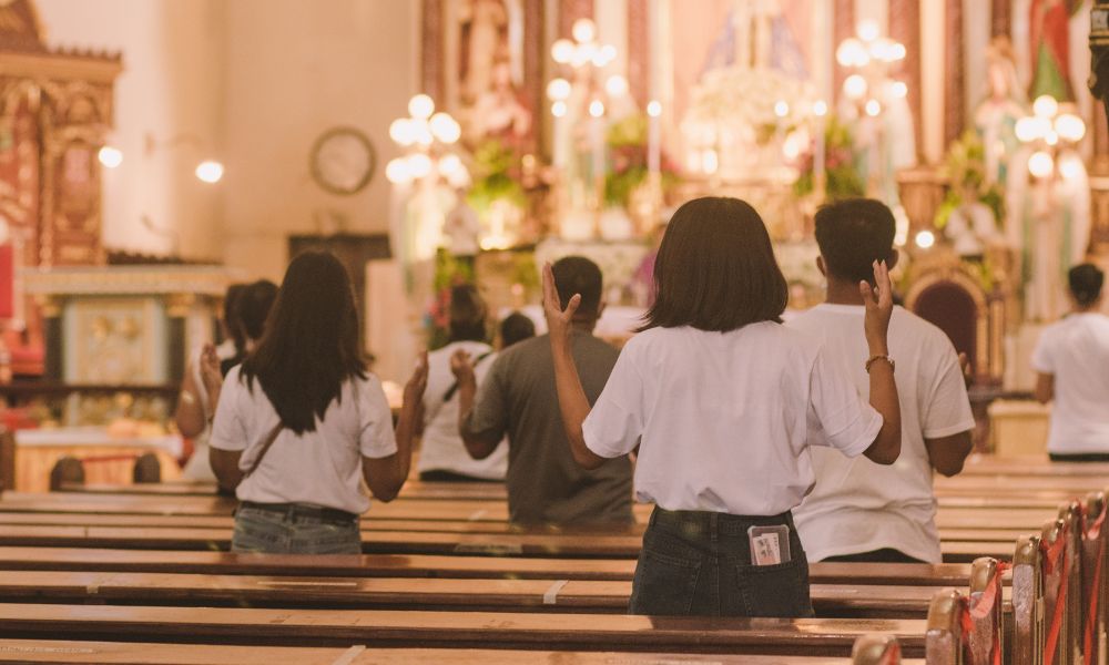This is an image of people with their hands up in praise during the middle of a mass.
