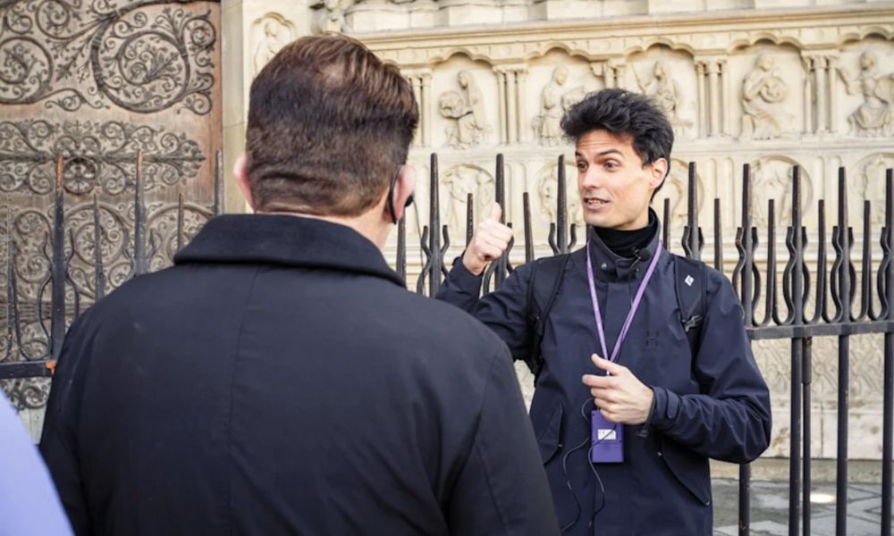 This is an image of a tour guide explaining things to a group and pointing back at the cathedral.