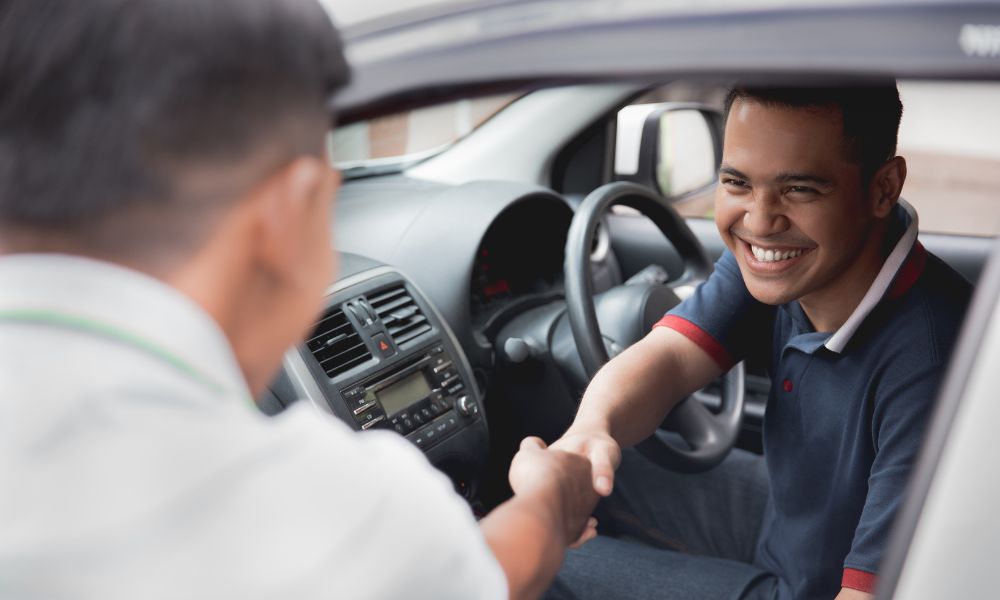 This is an image of a rideshare. One man is shaking hands with another as if they just met. Both are smiling.
