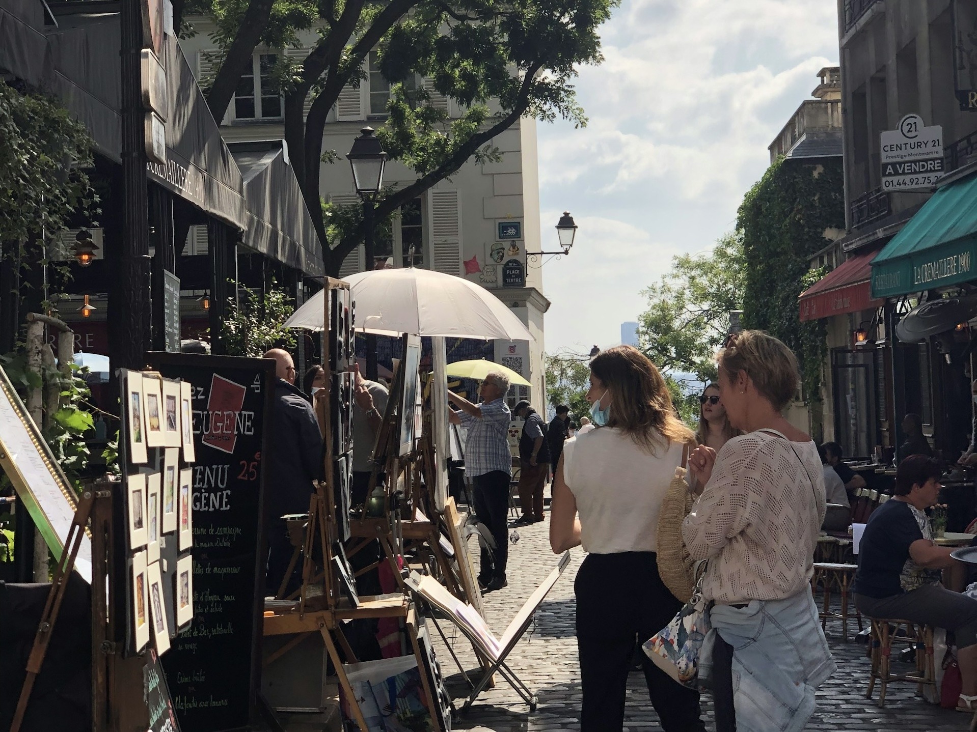 Two people walk along a busy street market in Paris.