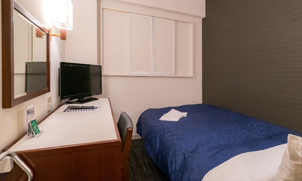 Paris hotel advice: This is an image of a small hotel room with a bed and desk pressed up against the wall.