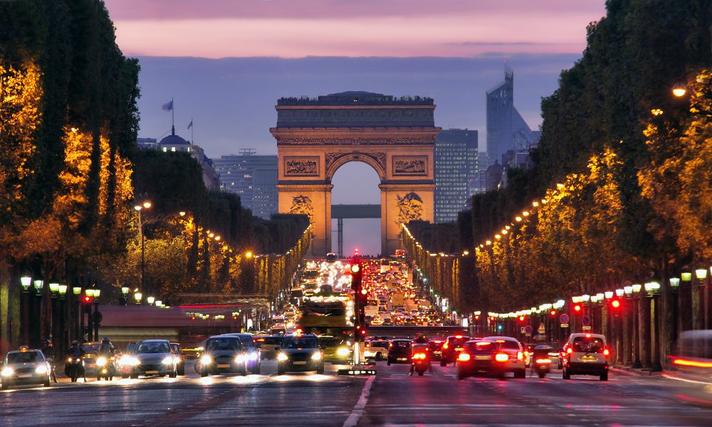 Paris hotel advice: This is an image of Champs Elysees street with cars blazing down and sunset in the background.
