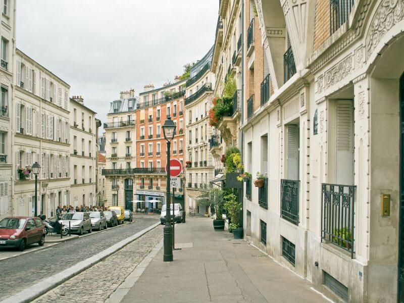 This is an image of a winding street full of traditional Parisian buildings and more.