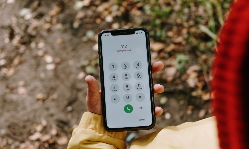 This is an image of a person holding their phone with the European emergency number in it.