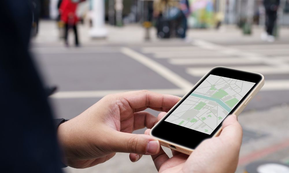 This is an image of a person holding a phone looking at directions on a street.