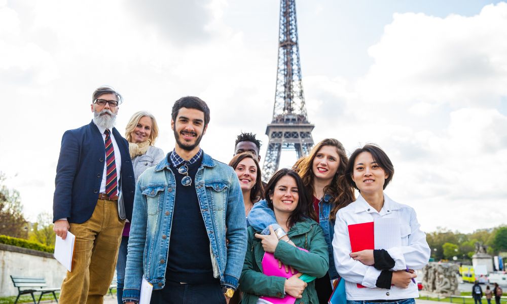 This is an image of a tour group posing together in front of the Eiffel Tower.