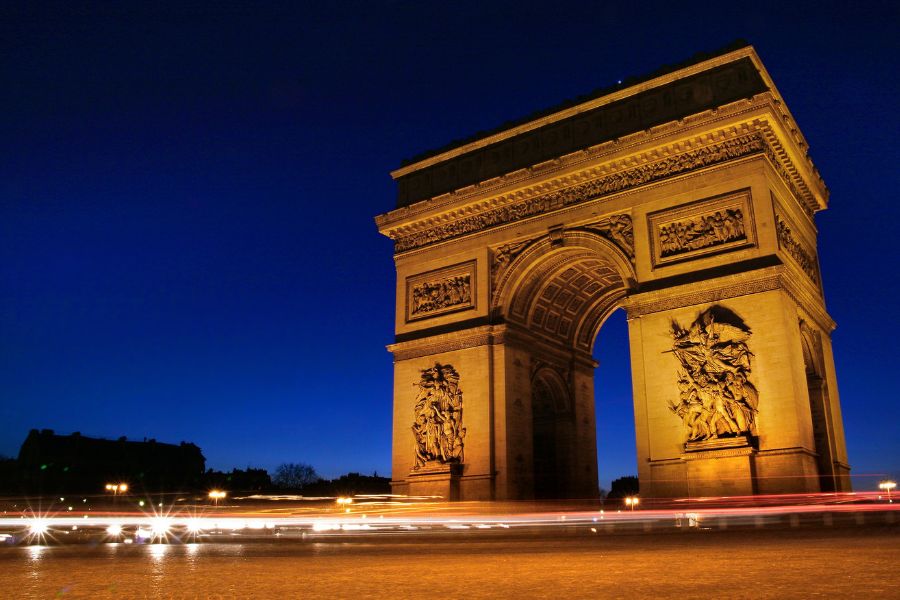 This is an image of the Arc De Triomphe late at night with no traffic on the roundabout around it.