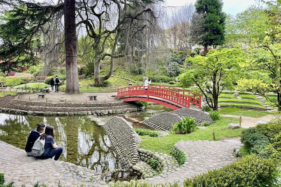 This is an image of a beautiful little park with a foot bridge and a small pond underneath it.