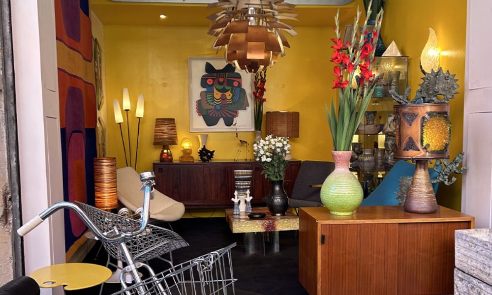 This is an image of an antique stall at a market with vases, bikes and a bunch of cool wooden furniture.